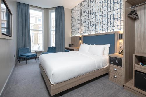 a hotel room with a bed and a desk and chair at Brit Hotels Earls Court in London
