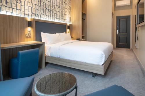 a bedroom with a large bed and a blue chair at Brit Hotels Earls Court in London