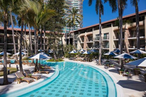 a swimming pool with chairs and umbrellas next to a building at The Hacienda at Krystal Grand Puerto Vallarta- All Inclusive in Puerto Vallarta