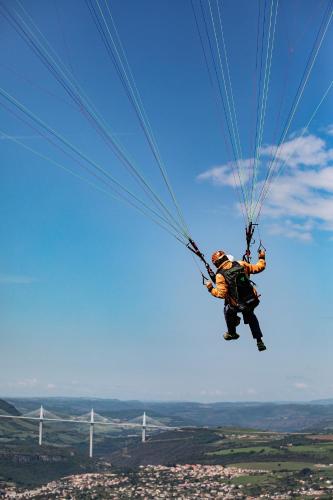 a man hanging from a parachute in the sky at Le Chat Blanc Gîte in Versols-et-Lapeyre