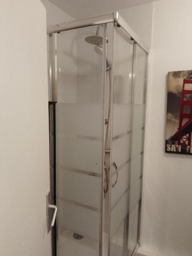 une douche avec une porte vitrée dans une salle de bain dans l'établissement GuestHouse Familial de 1 à 4 personnes de 42m2-Rez de Chaussée-Vues sur Rue et Patio Privé Ombragé - Séjour,Chambre séparée,Cuisine,Salle de Bain,Lit double et 2 canapés lits dépliant - Entrée côté Rue Berzélius-5 minutes du Métro Brocante ,bus 31,54,74, à Paris