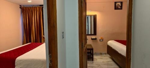 a hotel room with two beds and a mirror at Ponmurugan Residency in Kodaikānāl