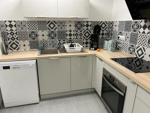 une cuisine avec des armoires blanches et du carrelage noir et blanc dans l'établissement Appartement deux chambres centre ville, à Charleville-Mézières
