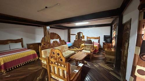 a room with two beds and chairs and a tv at Hotel Colonial Taxco in Taxco de Alarcón