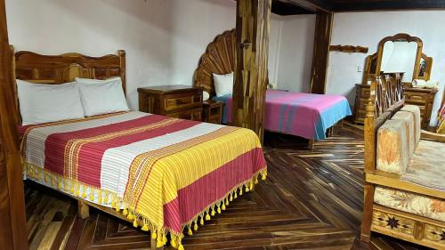 a bedroom with two beds and a mirror at Hotel Colonial Taxco in Taxco de Alarcón