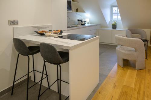 a kitchen with a island with a sink and two bar stools at Résidence Le Mésange, Strasbourg centre-ville in Strasbourg