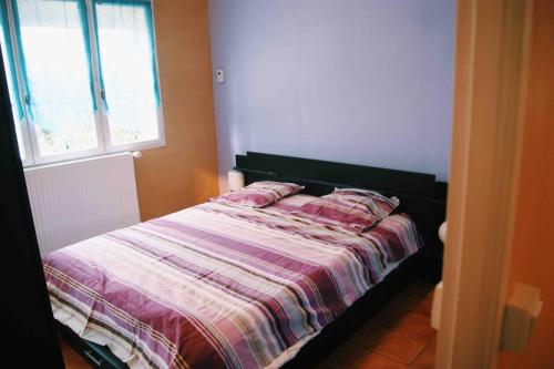 - un lit avec une couette rayée dans une chambre dans l'établissement Le clos des vignes, à Montlouis-sur-Loire