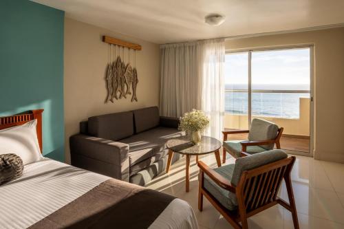 a bedroom with a bed and a couch and a table at Don Pelayo Pacific Beach in Mazatlán