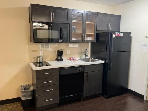 a kitchen with black appliances and a black refrigerator at Candlewood Suites Eugene Springfield by IHG in Eugene