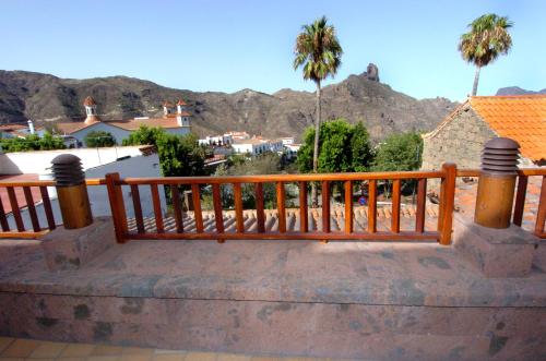 a wooden bench on a balcony with palm trees and mountains at HOTEL FONDA de La TEA in Tejeda