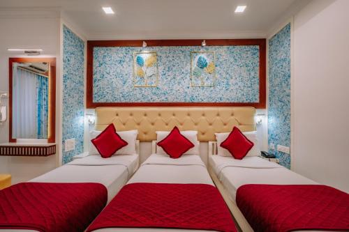 two beds in a room with red pillows at Excellency Airport Hotel in Angamali