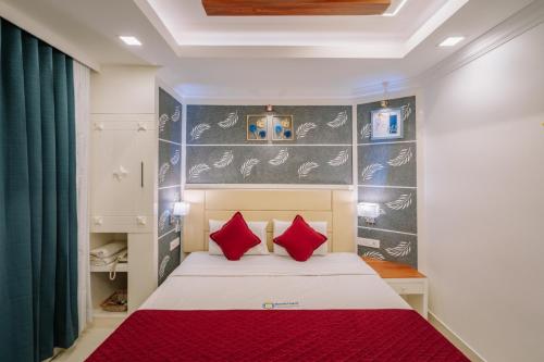 a bedroom with a bed with red pillows at Excellency Airport Hotel in Angamali