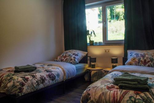 a room with two beds and a window at Ferienhaus AlbSommer - FehlaTal in Burladingen