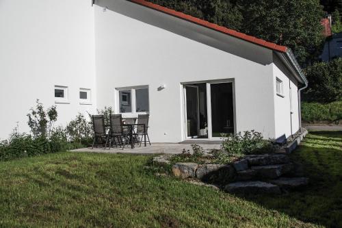 a white house with chairs and a patio at Ferienhaus AlbSommer - FehlaTal in Burladingen