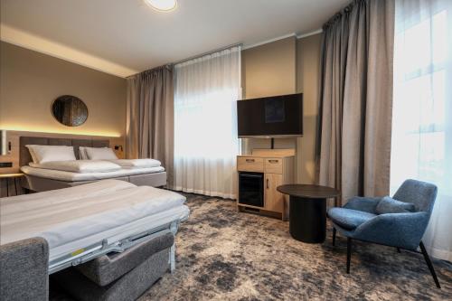 a hotel room with two beds and a tv and a chair at Thon Partner Notodden in Notodden