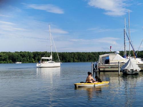 a man in a kayak in the water with boats at 2-Etagen-Wohnung im Haus am See von Berlin in Zeuthen