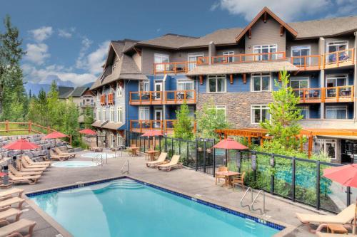 a pool at a resort with chairs and umbrellas at Mountain Luxe in Canmore