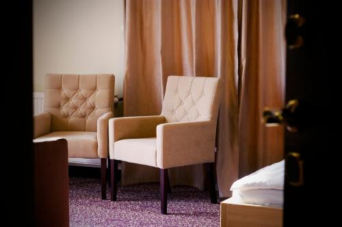 two chairs and a chair in a room with curtains at Xavin Wellness Hotel & Restaurant in Harkány