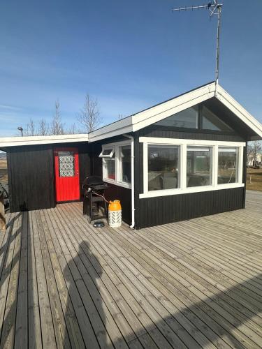 a black building with a deck with a table at Cozy Kálfhóll in South Iceland in Hraunvellir