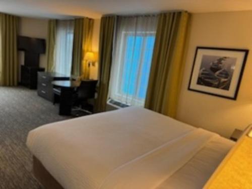 a hotel room with a large bed and a desk at Candlewood Suites Eugene Springfield by IHG in Eugene