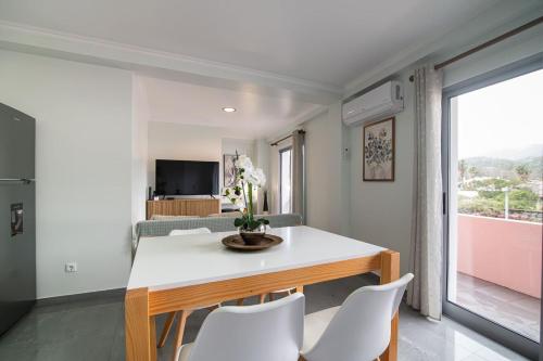 a dining room with a table and white chairs at Natural Living Vacations in Furnas
