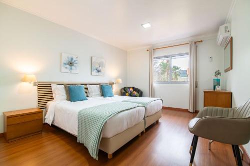 a bedroom with a bed with blue pillows and a chair at Natural Living Vacations in Furnas