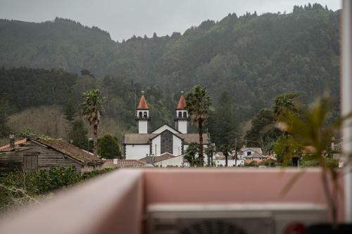 a church in a small town with mountains in the background at Natural Living Vacations in Furnas