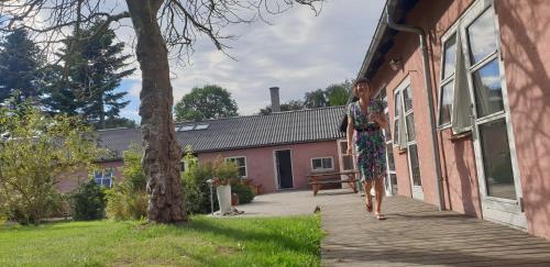 a woman walking down a wooden walkway next to a building at Rødegaard Mols in Knebel