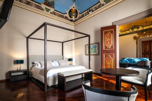 a bedroom with a bed and a table and chairs at Bosone Palace in Gubbio