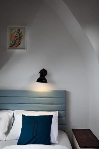 a bed with a blue headboard and a light above it at Long Story Short Hostel & Café in Olomouc