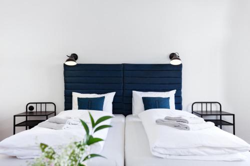 two beds with white sheets and blue headboards at Long Story Short Hostel & Café in Olomouc