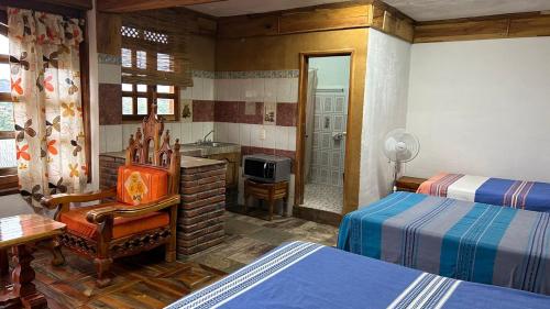 a bedroom with two beds and a chair and a bathroom at Hotel Colonial Taxco in Taxco de Alarcón