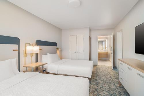 a hotel room with two beds and a flat screen tv at Homewood Suites By Hilton Thornton Denver in Thornton