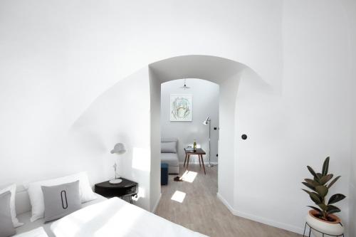 a bedroom with a white bed and a room with a table at Long Story Short Hostel & Café in Olomouc