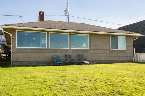 a house with two chairs and a table in the yard at Beach Bungalow - Roads End in Lincoln City