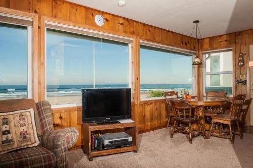 a living room with a television and a table with chairs at Beach Bungalow - Roads End in Lincoln City