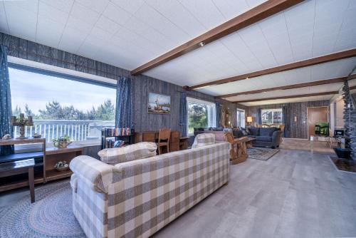 a living room with couches and a large window at Ebbing House in Lincoln City