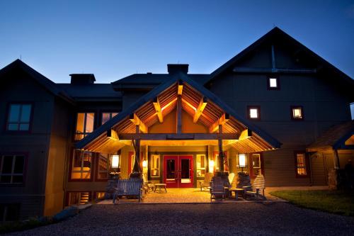 a large wooden house with chairs in front of it at Auberge de Montagne des Chic-Chocs Mountain Lodge - Sepaq in Sainte-Anne-des-Monts