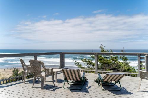 a deck with chairs and a table and a view of the ocean at Ebbing House in Lincoln City