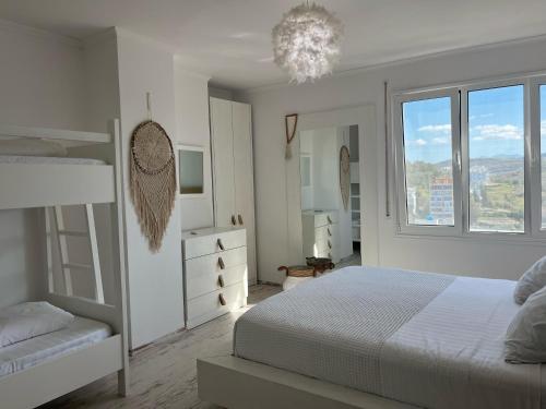 a white bedroom with a bed and a window at Beachfront Marilyn in Durrës