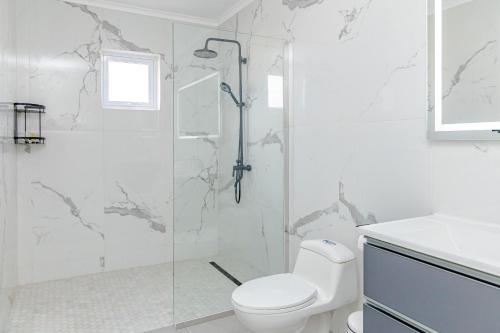 a white bathroom with a shower and a toilet at SPECIAL OFFER !! 7 min to Beach - Newly-Renovated Modern Luxury Home in Paradera