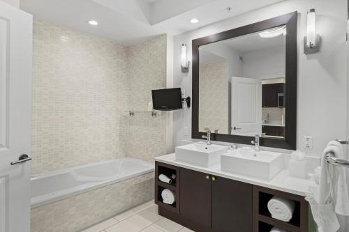 a bathroom with two sinks and a tub and a mirror at Provident Doral At The Blue in Miami