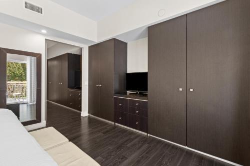 a bedroom with a bed and a tv and wooden cabinets at Provident Doral At The Blue in Miami