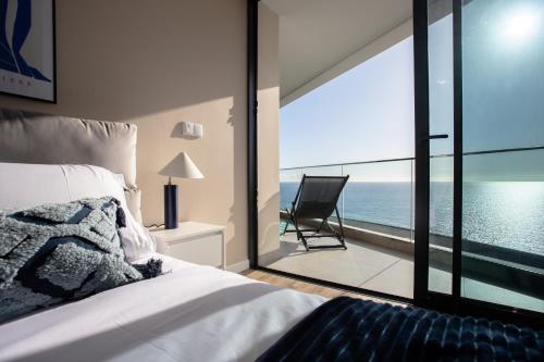 カマラ・デ・ロボスにあるOceanfront Elegance Madeira Retreatのベッドがあり海が見える寝室