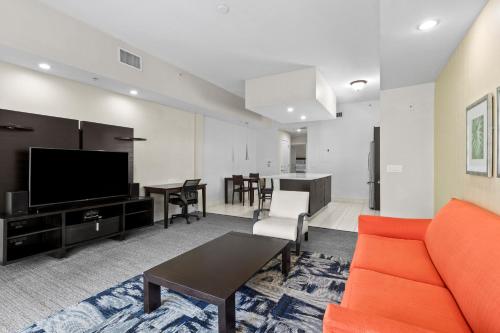 a living room with an orange couch and a flat screen tv at Provident Doral At The Blue in Miami