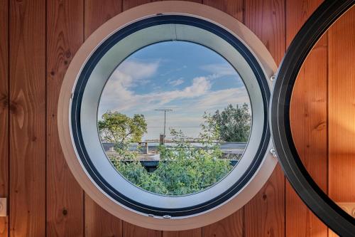 - une fenêtre ronde dans un mur en bois avec vue dans l'établissement Villa Sangla - Accès plage - Piscine - Climatisation, à Lège-Cap-Ferret