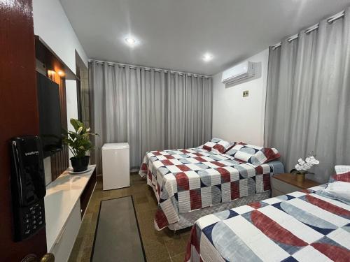 a hotel room with two beds and a television at Studio Sol - 3 min do Mossoró Cidade Junina in Mossoró