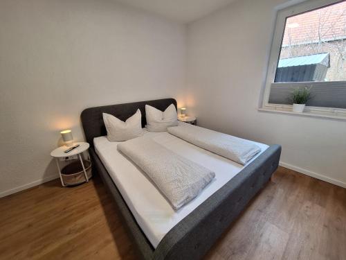 a bedroom with a bed with white sheets and a window at Ferienwohnung auf dem Pferdehof am Gestütsweg in Alt Krenzlin