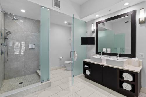 a bathroom with two sinks and a shower with a mirror at Provident Doral At The Blue in Miami