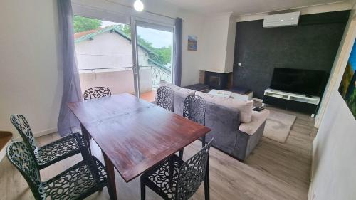 un salon avec une table, des chaises et un canapé dans l'établissement Le Duplex Pyrénéen - Terrasse - Clim - Parking, à Lons